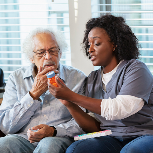 Women aide reminding senior man about taking his medication