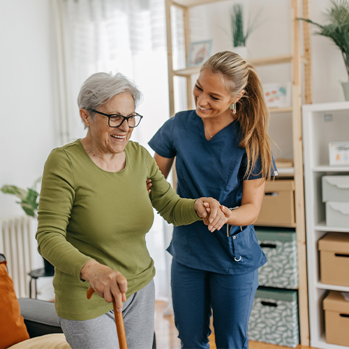 Female aide providing fall prevention to senior woman with cane