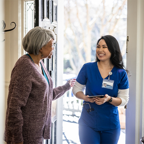 A woman nurse greeting senior woman client at door for wellness visit