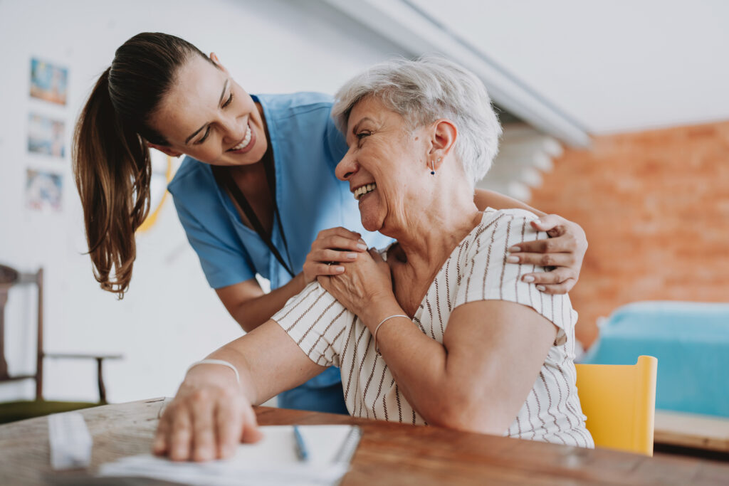 Friendly, reliable female nurse embracing older woman client